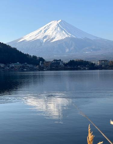 Mount Fuji reflected in a serene lake with a clear sky.