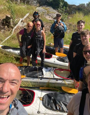 Group of people in kayaking gear posing with kayaks.