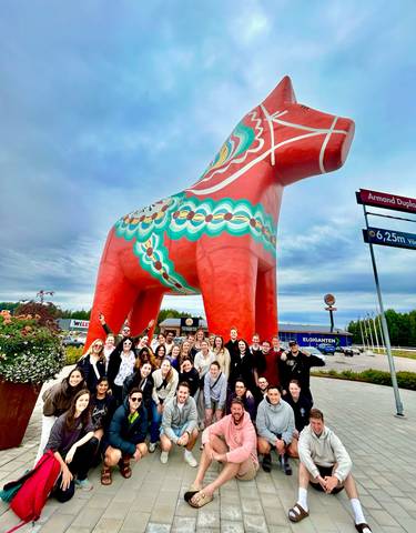 Group posing in front of a giant red Dala horse statue.
