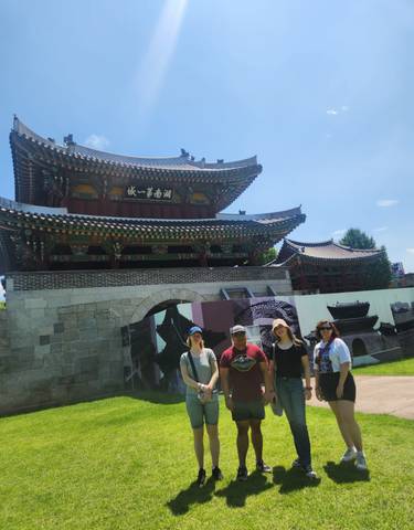 Group of people posing in front of a traditional Korean building.