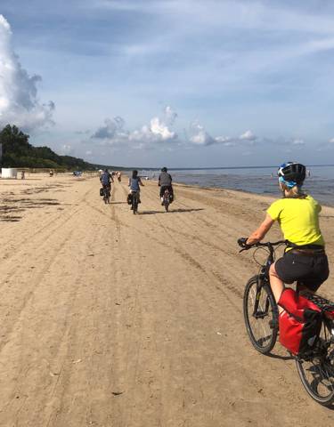 Cyclists riding along a sandy beach.