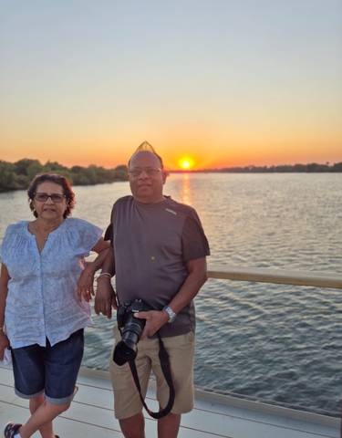 Two people standing by a river during sunset.