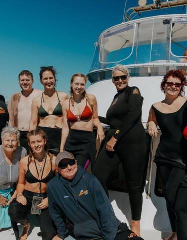 A large group of people posing on a boat, likely on a tour.