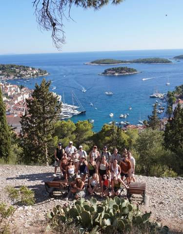 Group of people posing with a view of the sea and islands.