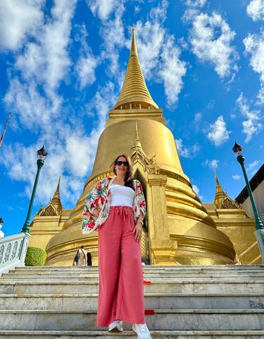 Person posing in front of a golden temple or stupa.