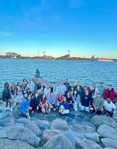 Large group posing with a waterfront and cityscape behind.