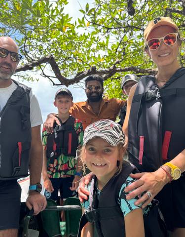 Group of people in life jackets on a boat ride through mangroves.