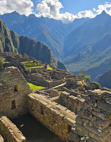 Machu Picchu ruins with visitors, surrounded by mountains.