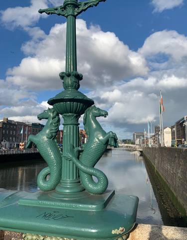 Decorative lamppost with horse statues by a river.