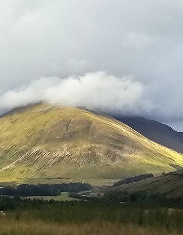 A mountain partially covered by clouds under a dramatic sky.