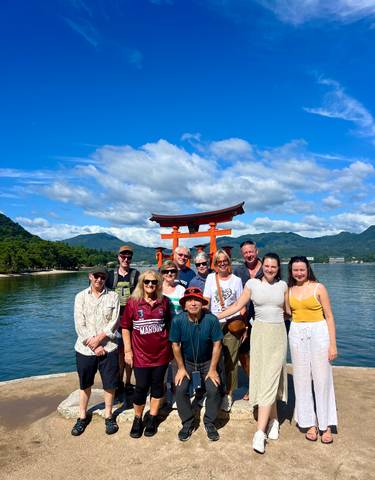 Group posing in front of the iconic Torii gate at the water's edge.