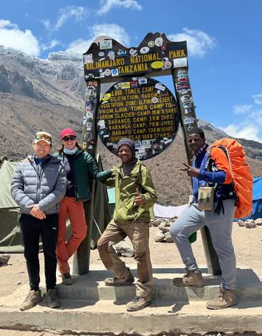 People posing under the Kilimanjaro National Park sign.