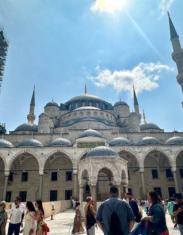 Historic mosque with domes and a scaffolded minaret.