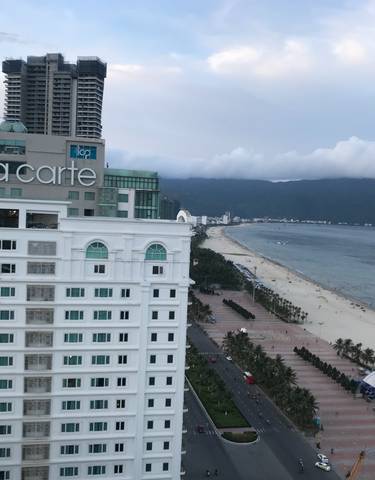 A view of a beachside hotel with the sea and mountains.