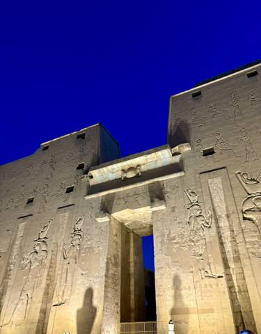 Illuminated temple facade with hieroglyphs.