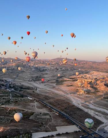 A sky full of colorful hot air balloons over a landscape.
