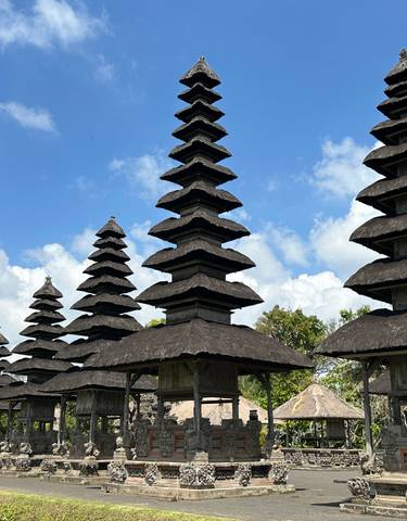 Balinese temple with multiple tiered roofs and blue sky background.