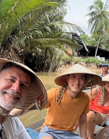 Group of people in traditional hats on a boat in a river.