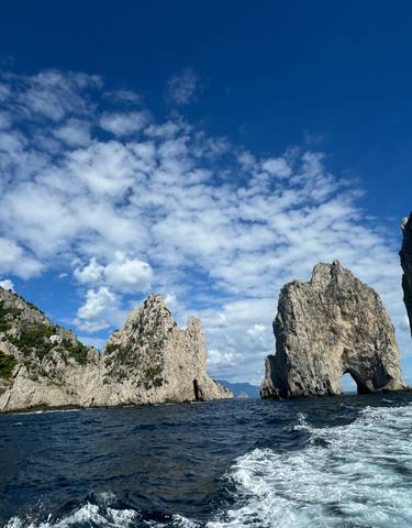 Beautiful rock formations in the sea under a partly cloudy sky.