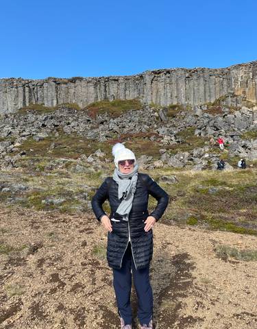 A person posing with a rocky cliffs backdrop.