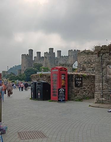 Castle with people and a red phone booth in front.
