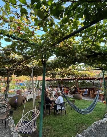 Garden restaurant with people dining under vine-covered trellis.