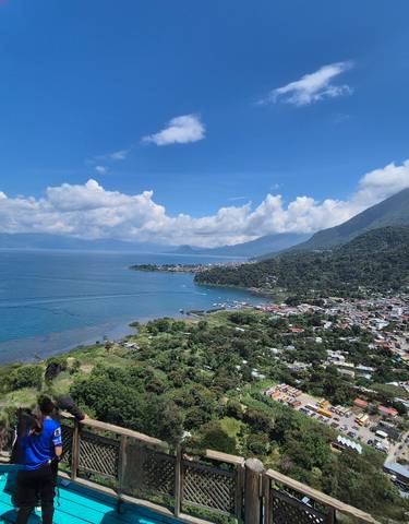 Panoramic view of a town by a large lake with people on a lookout.