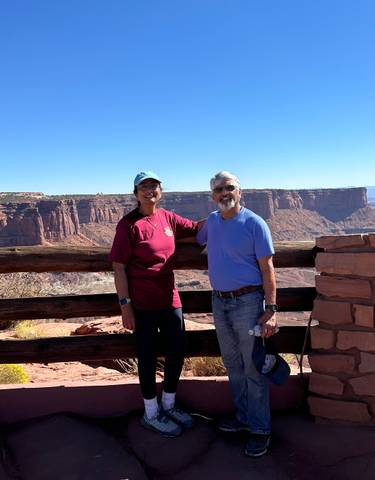 Two people posing in front of a canyon landscape.