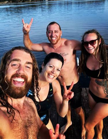 Group of friends swimming and posing by the water.