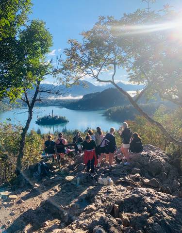 Group of people overlooking a picturesque lake and forest.