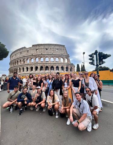 A group of people posing in front of the Colosseum.
