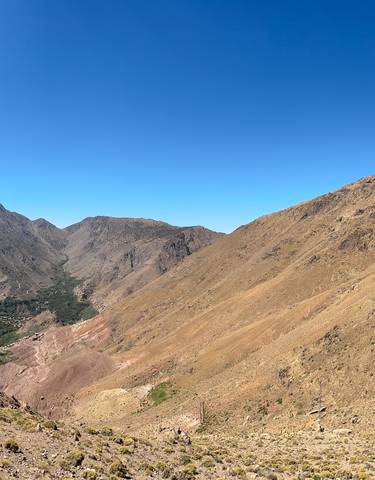 A panoramic view of a mountainous landscape under a clear blue sky.