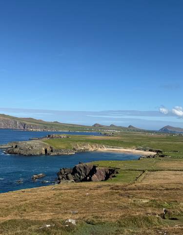 Coastal view overlooking a jutting peninsula and distant mountains.