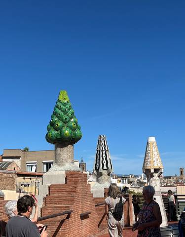 Colorful mosaic chimneys on a rooftop, iconic Gaudi design.
