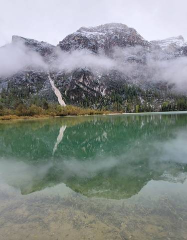 Scenic view of a clear lake reflecting mountains with clouds.