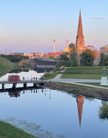 Scenic park with canals and church spire at dusk.