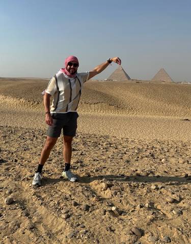 Person posing in front of the pyramids.