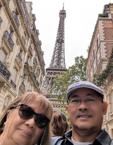 Two people posing in front of the Eiffel Tower with surrounding buildings
