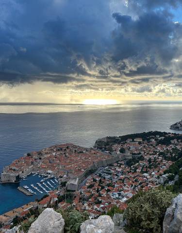 Aerial view of Dubrovnik with the ocean and dramatic sky.