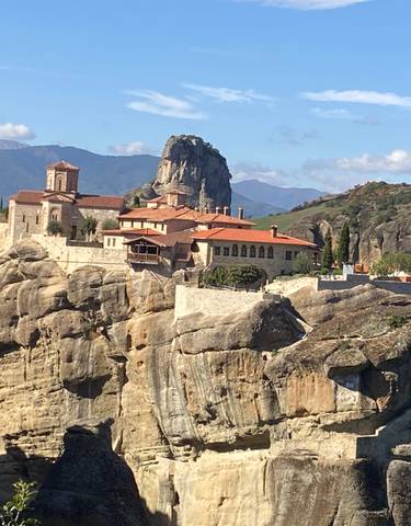 Monastery built on a cliff in a mountainous landscape.