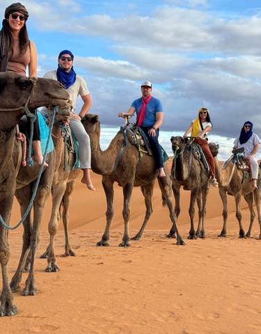 Group of people riding camels in the desert.