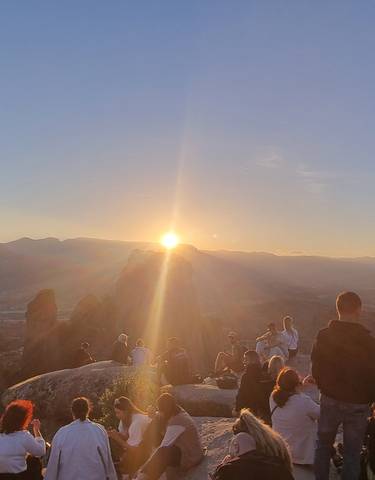 Group of people watching sunset over the mountains.