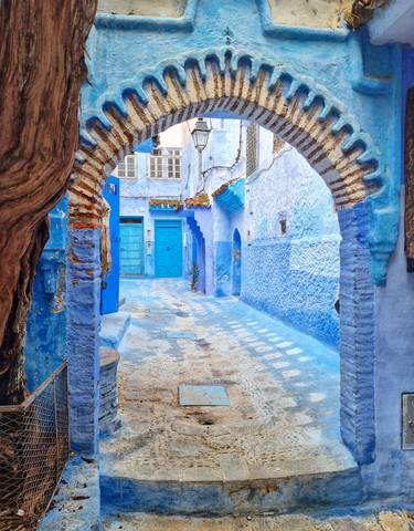 A vibrant blue alleyway with arches and detailed doorways.