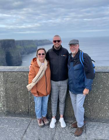 Three people standing on a cliff overlooking the ocean