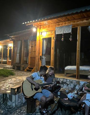 People enjoying music and tea on a porch at night.