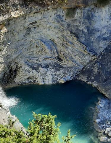 Waterfall and a blue water pool amidst rocky terrain.