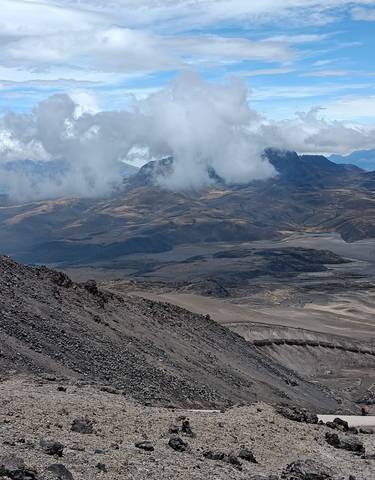 A vast landscape with rocky terrain and clouds over a mountain.