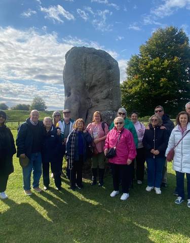 A group of people posing in front of a large stone monument.