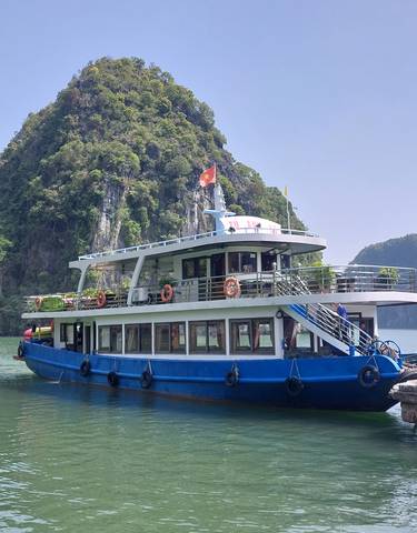 Tourist boat docked in a bay surrounded by limestone mountains.