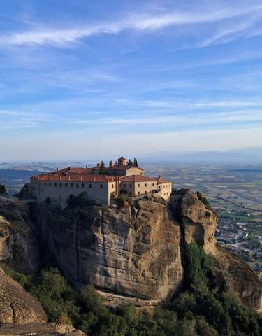 Monastery perched on a rock with landscape view.